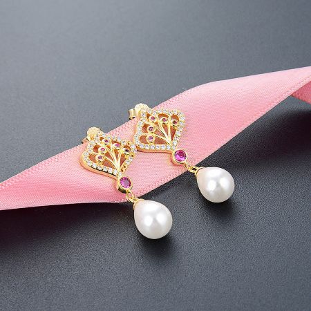 Detailed view of the gold butterfly pearl drop earrings showcasing the intricate gemstone work.
