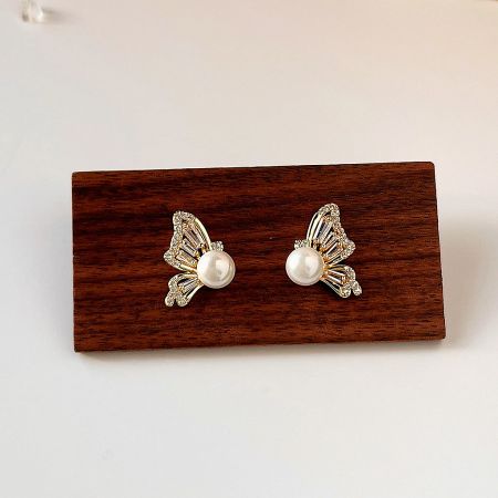 The set of gold butterfly earrings with pearls and gemstones displayed on a wooden block.