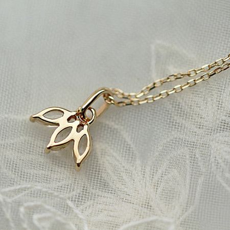 Charming gold butterfly pendant necklace from the set, displayed on a delicate lace surface.