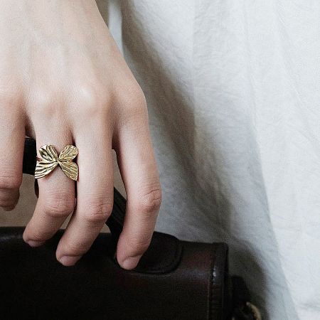 Detailed view of the elegant gold-plated butterfly ring on a finger.