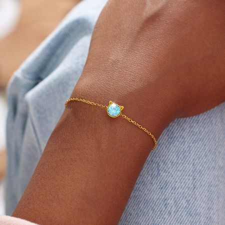 The sterling silver cat bracelet with its distinctive cat-ear design and blue gemstone, elegantly styled on a wrist.