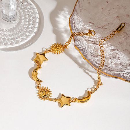 Close-up of a gold stainless steel bracelet with moon, sun, and star charms.