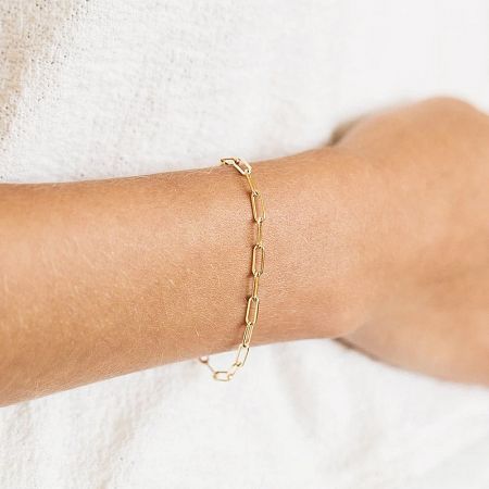 A woman wearing the gold paper clip chain bracelet.