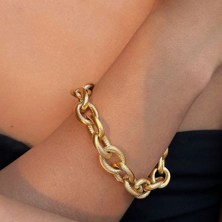 A model wearing the gold chain link bracelet from the set to showcase its scale and style on the wrist.