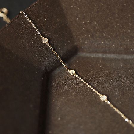 925 Sterling Silver Gold Zircon Disc Bracelet (Set of 5) - A close-up of the 925 Sterling Silver Gold Zircon Disc Bracelet, showcasing its delicate chain and three sparkling circular charms on a textured background.