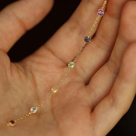 Full view of the delicate gold chain bracelet adorned with colorful gemstones.