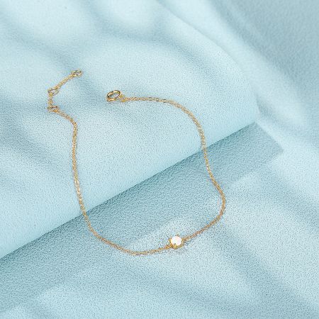 Product shot of the gold chain bracelet with a single white opal gemstone.