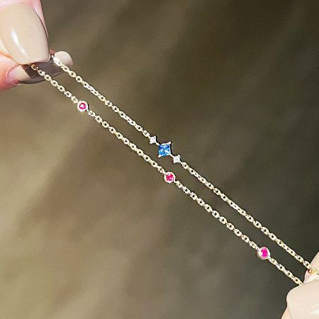 Full view of the two-layered gold chain bracelet with multiple colorful zircon stones.