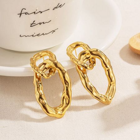 Lifestyle image of the gold chain-link earrings next to a white teacup.