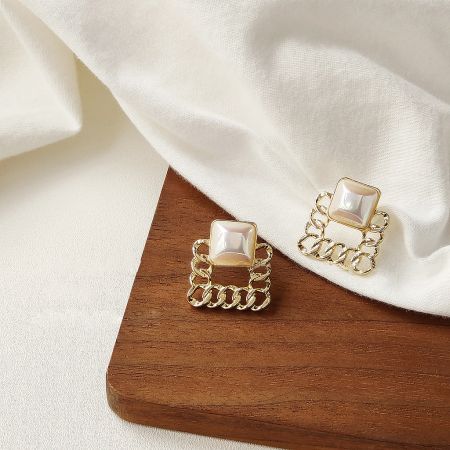 Detailed view of the square pearl stud earrings with a sophisticated gold chain-link design.