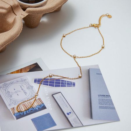 A detailed view of the gold-plated stainless steel bracelet, showing the quality of the chain and stones.