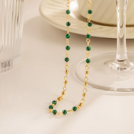 The full set of five gold and green beaded necklaces arranged artfully.