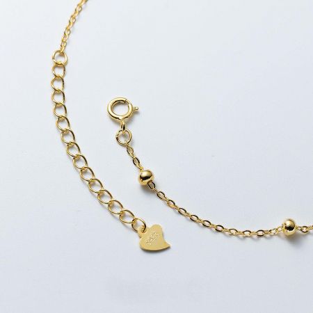 Detail shot showing the S925 sterling silver stamp on the clasp of the gold-plated heart charm bracelet.
