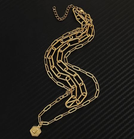 Close-up of the gold chain and hexagonal pendant, showcasing the polished finish and intricate details.