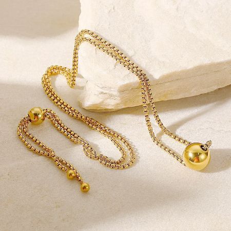 Detailed view of the gold pull-box chain and spherical pendant.