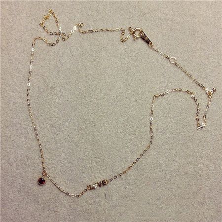 Full view of the gold chain necklace with the striking red gemstone love pendant.