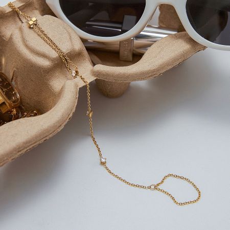 The dainty gold finger bracelet displayed in a jewelry case, highlighting its sparkling cubic zirconia.