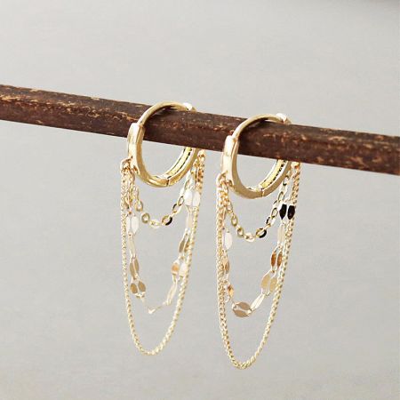 Detailed view of the gold chain earrings with reflective accents.