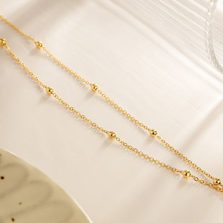 A product shot of the gold chain bracelet with beads, displayed for clarity and detail.