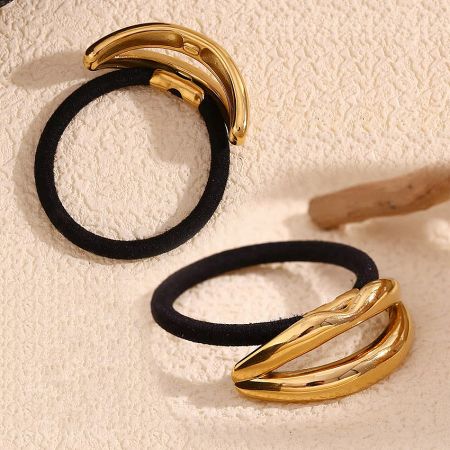 Detailed view of two black elastic hair ties with the gold-finished stainless steel lip charm.