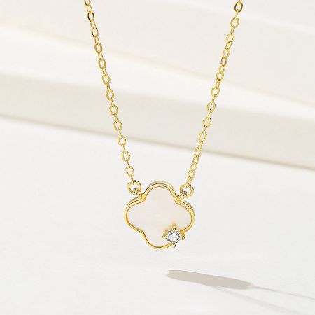 Collar de trébol de cuatro hojas de madreperla de plata esterlina 925. - Un primer plano de un collar de trébol de cuatro hojas de plata esterlina 925 con acabado dorado. El colgante está incrustado con madreperla y presenta una pequeña gema central.