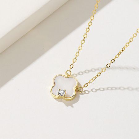 Angled view of the sterling silver clover pendant necklace, emphasizing its lustrous gold finish and intricate details.