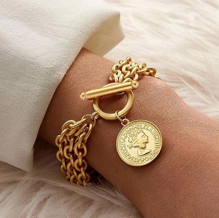 Detailed view of the gold coin pendant on the chain bracelet