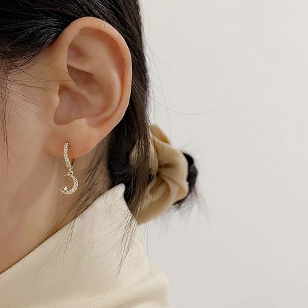 Model wearing the gold crescent moon huggie earring to show scale and style.