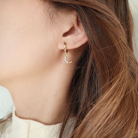 Detailed shot of the crescent moon huggie earring being worn, showing its delicate design.