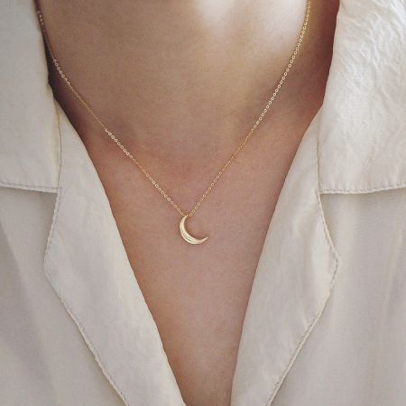 Model wearing the gold crescent moon pendant necklace, showcasing its length and style.