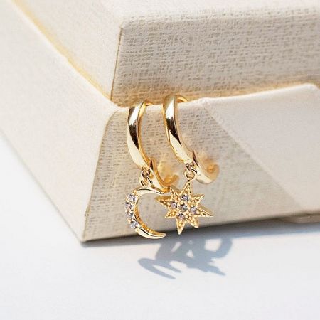Close-up of the gold-plated sterling silver earrings with star and moon charms.