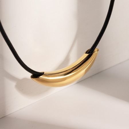 Close-up of the unique curved gold pendant on the stainless steel necklace.