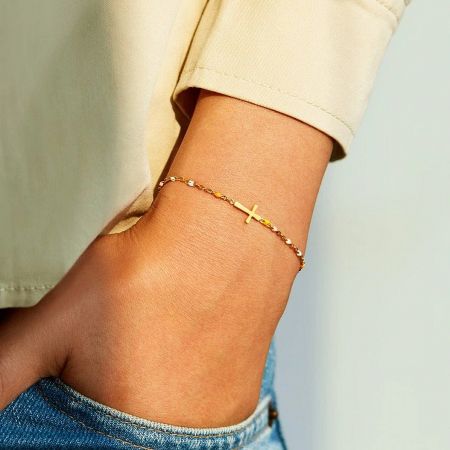 A model wearing the gold cross pendant bracelet, showcasing its elegant fit.