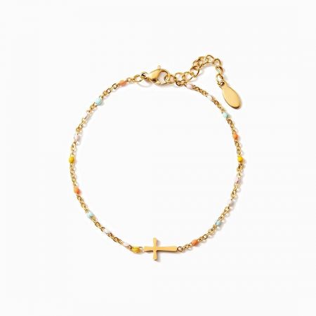 The gold cross pendant bracelet with multicolored beads laid flat for display.