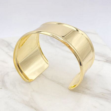 Angled view of the shiny gold cuff bracelet, highlighting its modern design.