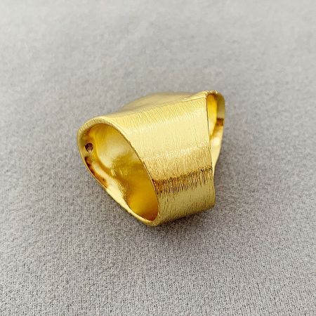 Detailed view of the polished gold finish on a drum-shaped brass ring.