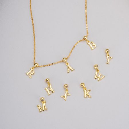 Close-up of a customizable gold necklace with various letter pendants.