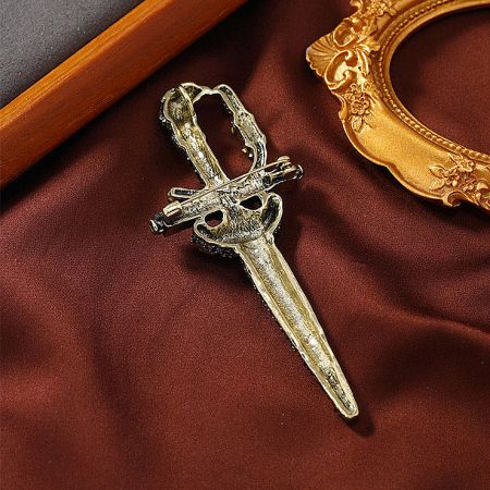 A unique gold-colored sword brooch with a distinctive heart-shaped hilt.