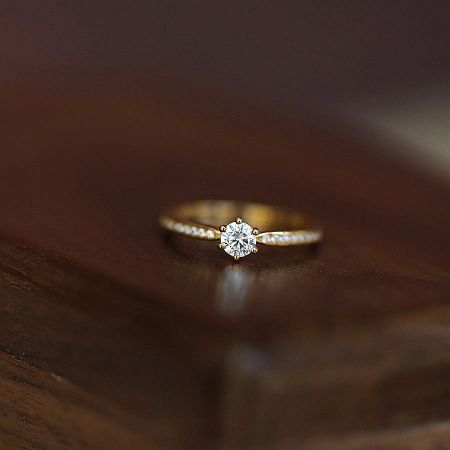 Detailed product shot of the six-prong solitaire ring, showcasing the brilliant center stone and polished band.