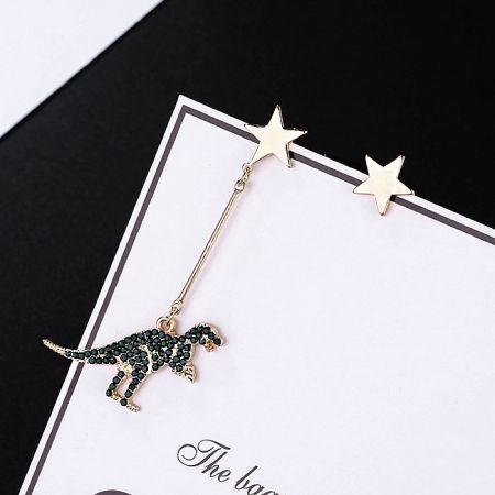 Close-up of the gold dinosaur dangle earring with emerald cubic zirconia detail.