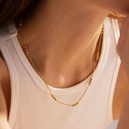 Model showcasing the double-layered look of the 18k gold beaded chain necklace.