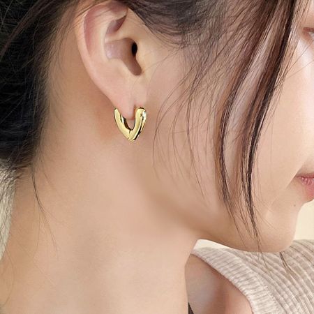 Detailed close-up of the gold V-shape hoop earring being worn.