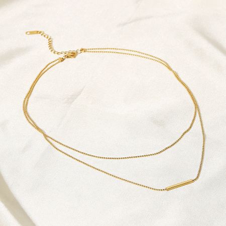 Full view of the gold double-layer necklace, displaying both chains and the central bar pendant.