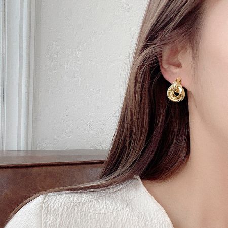 A model wearing the gold multi-layer stud earring to showcase its size and style.