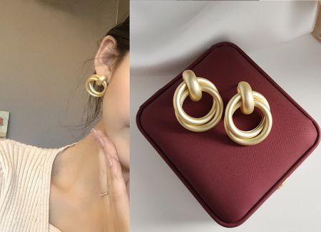 Model wearing the matte gold double-ring stud earrings to showcase their size and style.