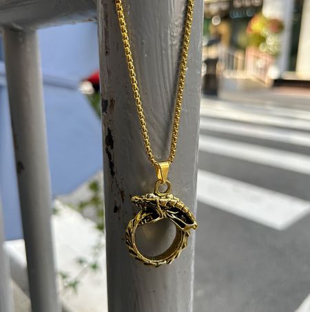 Close-up view of the gold dragon pendant, highlighting the intricate details of the circular design.