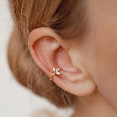 Close-up of a model's ear featuring an elegant gold dragonfly ear cuff.