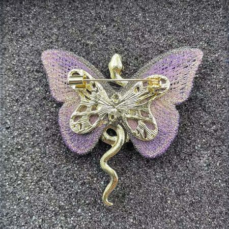 Detailed view of the brooch's unique design, combining a dragonfly body with a snake tail.