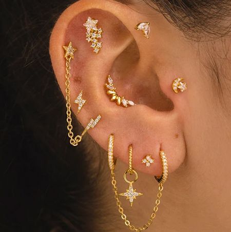 925 Sterling Silver Minimalist Tiny Stacking Stud Earrings - A close-up of a styled ear showcasing a collection of 925 sterling silver minimalist tiny stacking stud earrings with gold plating, including star and chain designs.