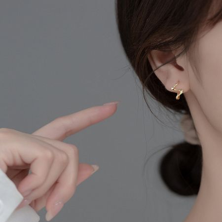 Close-up of the gold S925 wave cuff earring on an ear, showing its detailed sculptural form.